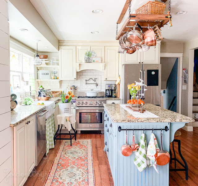 Cozy and Colorful Country Cottage Home Tour - Warm and inviting family kitchen, gas range, pot filler, worn wood floors, painted island, hanging pot rack. Cozy and Colorful Country Cottage Home Tour
