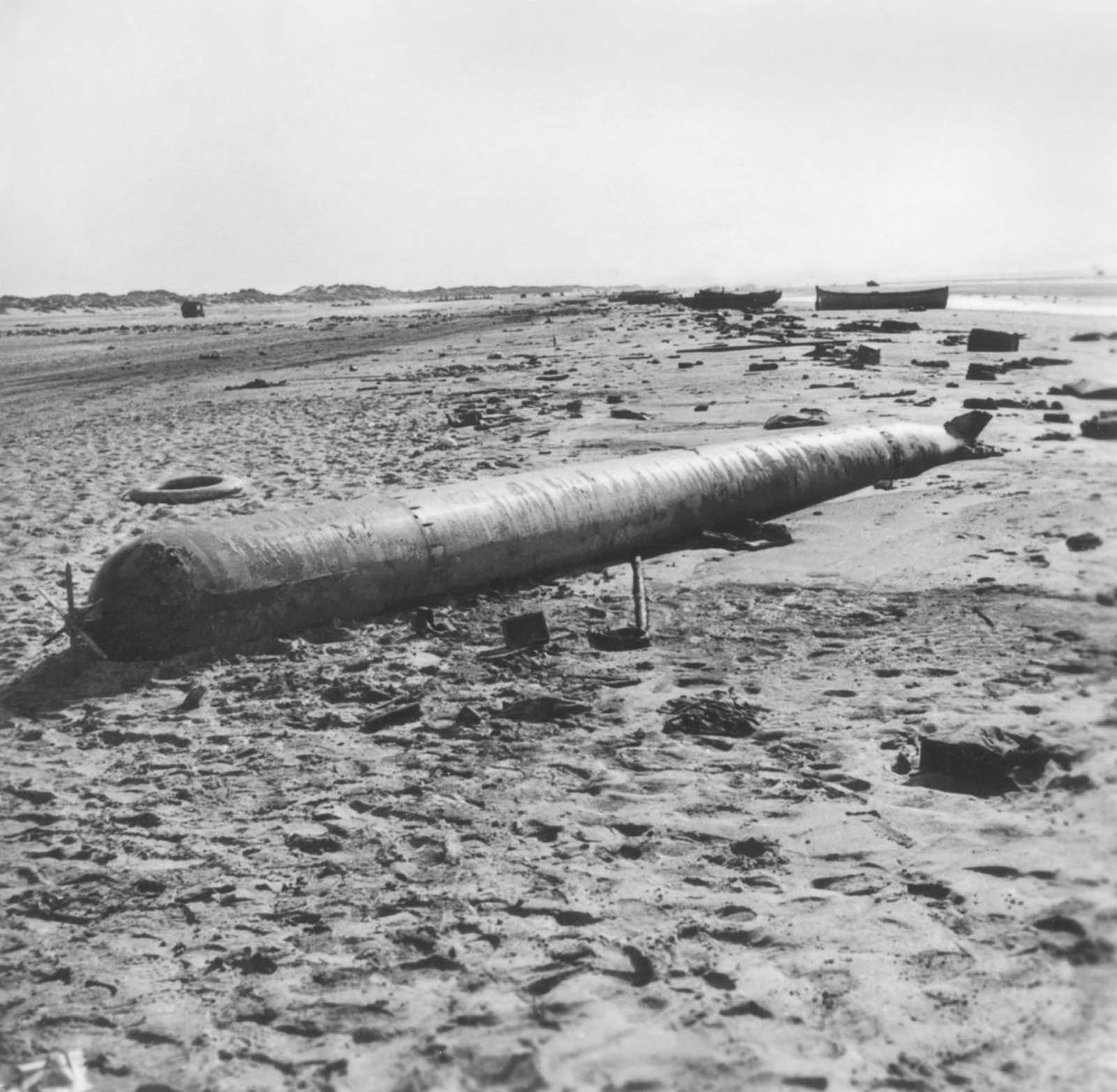 A beached torpedo lies among other abandoned equipment after the Allied evacuation.