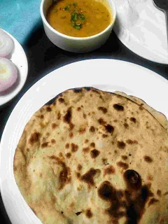 Serving tandoori roti in a plate, onion slices and dal in background