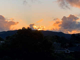 A photograph of a golden sunset over a dark hill.