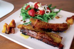 Costine di maiale con mele e zafferano su insalata di rucola, fragole e porri