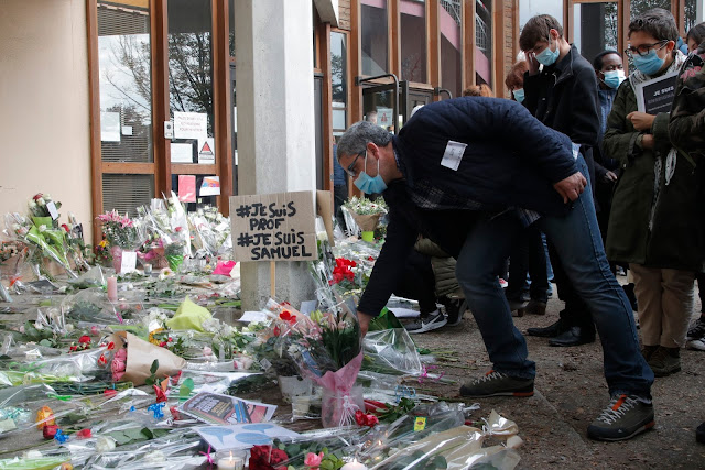 A man lays a flower outside College du Bois d’Aulne, the school where a slain teacher was working