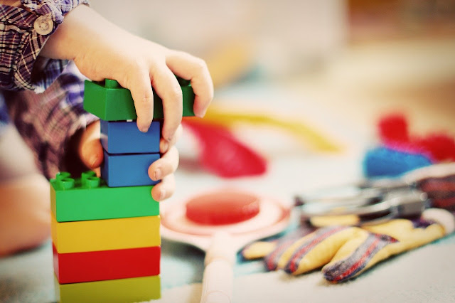 Pienen lapsen kädet rakentavat värikkäillä Dublo-palikoilla