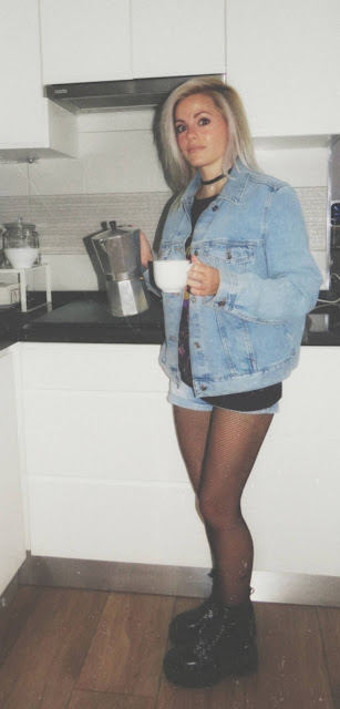 Estilo grunge con camiseta negra ancha con imagen del grupo The Doors, pantalón corto, medias de red pequeña, botas estilo militar y cazadora vaquera