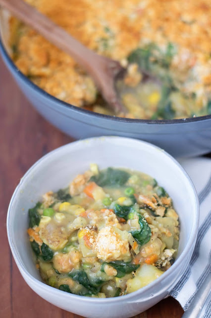 A bowl of the Easy Vegan Vegetable Casserole with the pan of casserole to the side.