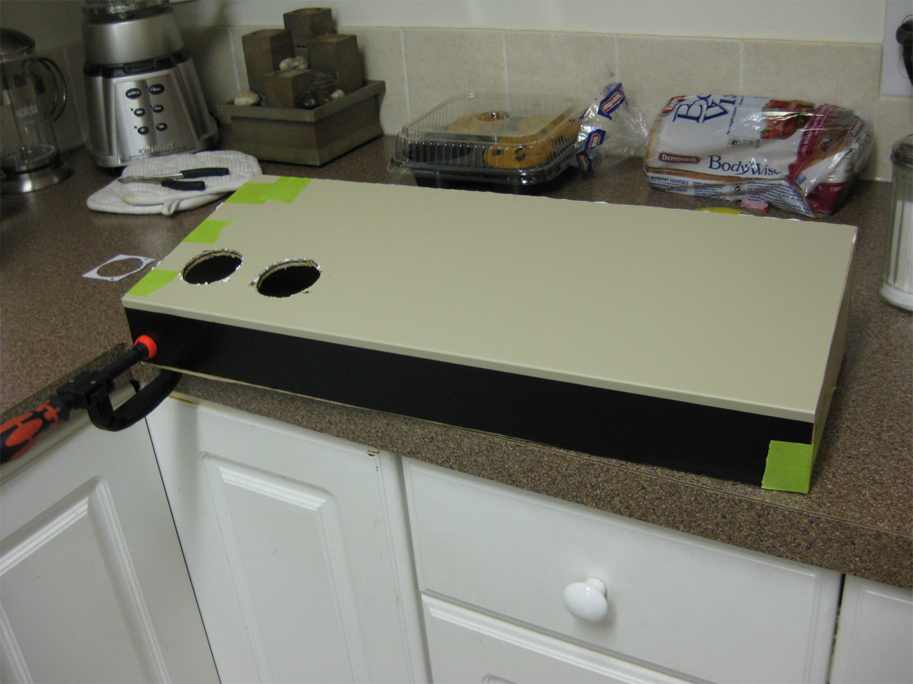 Wooden control panel being cladded with scrap wicker and black painted aluminum