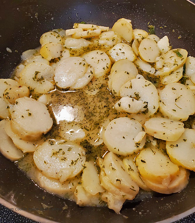 this is a large frying pan of sliced potatoes in a buttery cream sauce