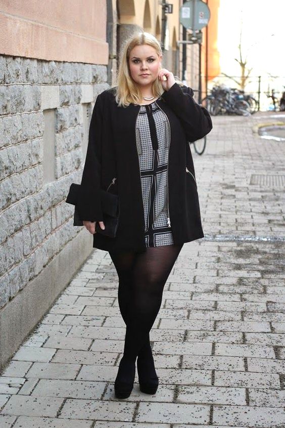 Plus size woman wearing a mini dress, back tights and black pumps