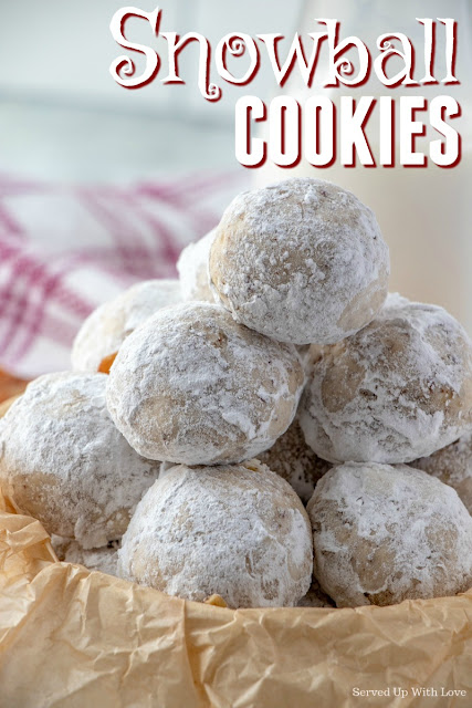 Close up picture of snowball cookies stacked in a parchment lined bowl