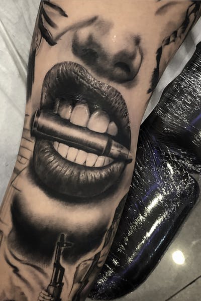 Tatuaje de boca mordiendo bala en grises