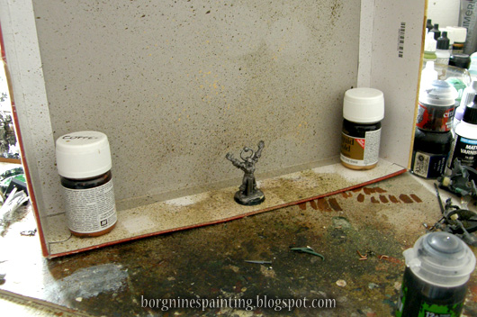 Photo showing my setup for miniature sprinkling - using a background of an old box weighted down with some paint pots.