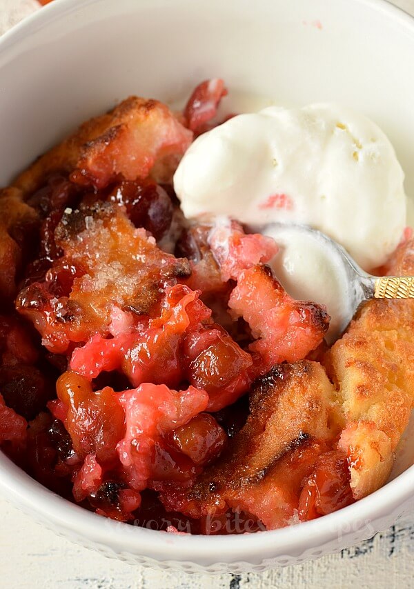 a close up of a white bowl with cherry cobbler with fresh cherries along with ice cream.jpg