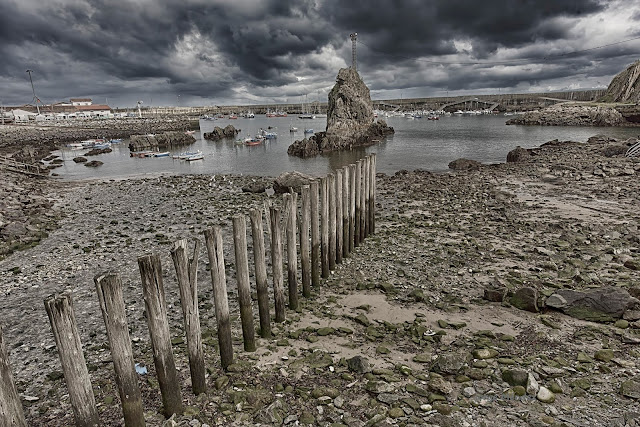 Playa del Oteo en el puerto de Cudillero Asturias. Estacas rompecorrientes frente a la Peñona