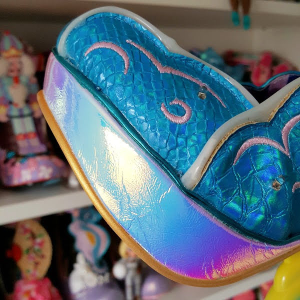 close up of holographic material platform in front of shoe shelves