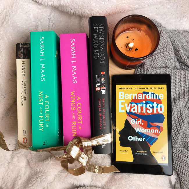 Top 10 books of 2020! Stack of books with their spines face up next to a kindle showing the cover of 'Girl, Woman, Other' by Bernardine Evaristo