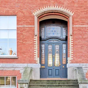 Tall gray Dublin door with ornate brick and stained glass on Northbrook Ave