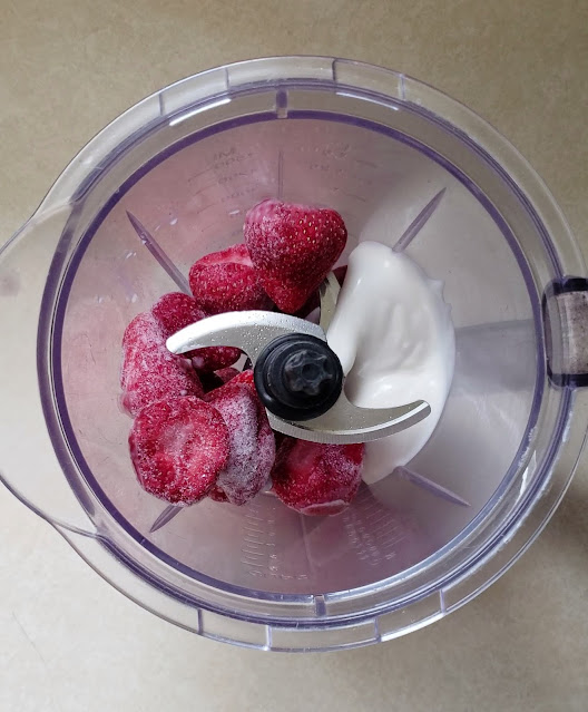 Frozen strawberries, vegan yogurt, and oat milk in a blender