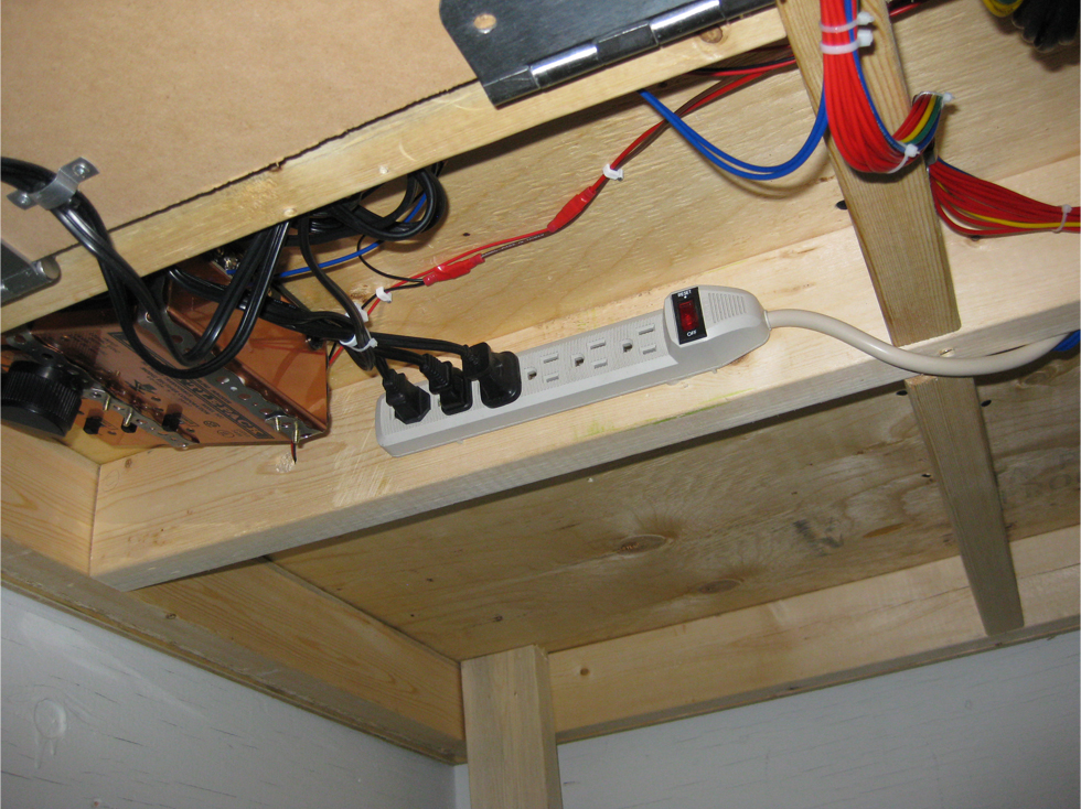 Underside of model railroad benchwork showing wiring and surge protector/power bar