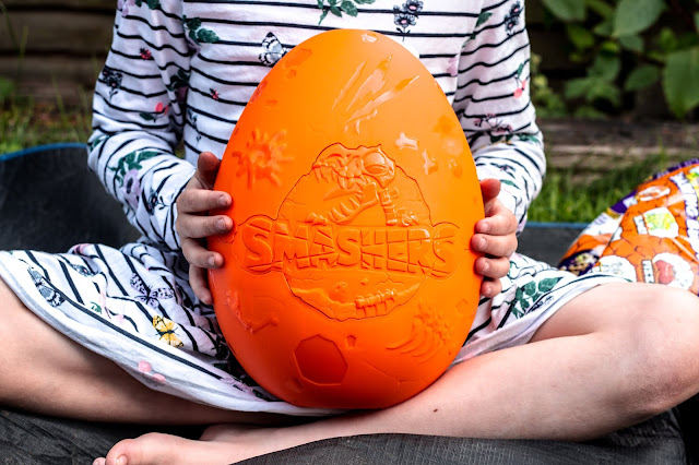 Child holding the plastic large egg shell ready to smash