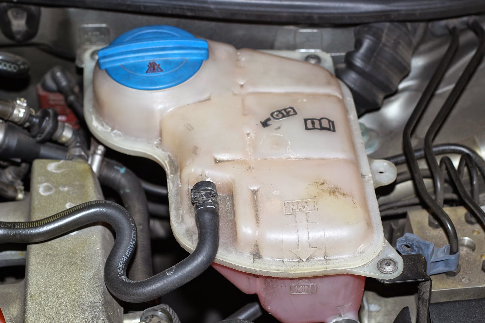 Remove three screws of the coolant tank, lift it away. Remove the coolant  sensor connector at the bottom of the tank. Gently lift it aside out of the  way.