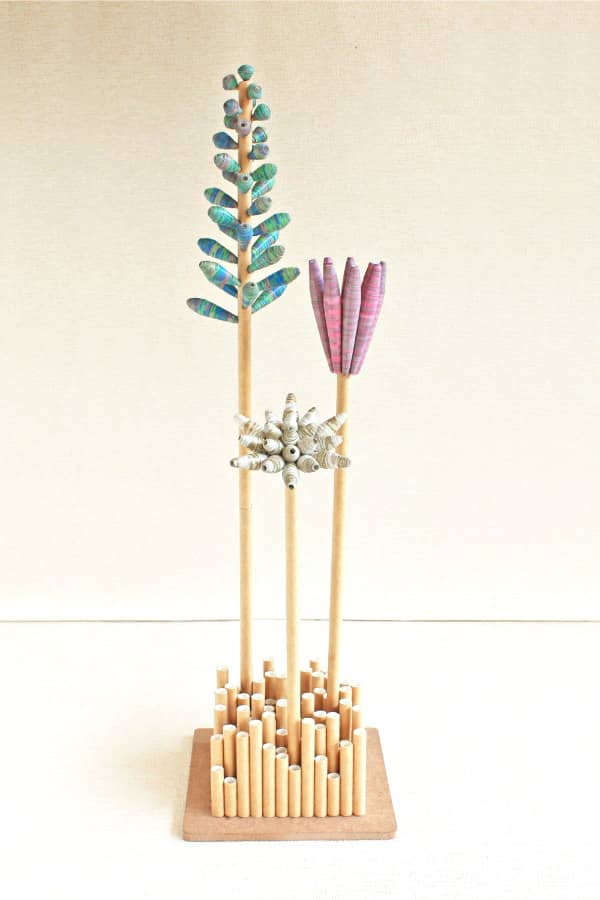 boeket van minimale papieren kraalbloemen weergegeven in een vaas bestaande uit rechtopstaande, holle papieren buizen in verschillende maten