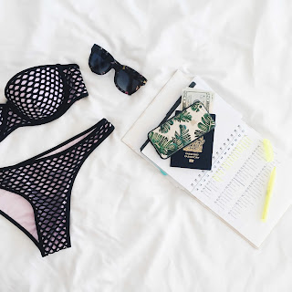 items laid out for packing; a bikini, sunglasses, and passport