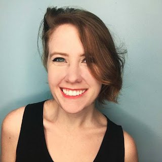 Ashley Poston's author photo. She is a pale, white woman with red hair that swoops over one eye. She is smiling and wearing a black sleeveless shirt.