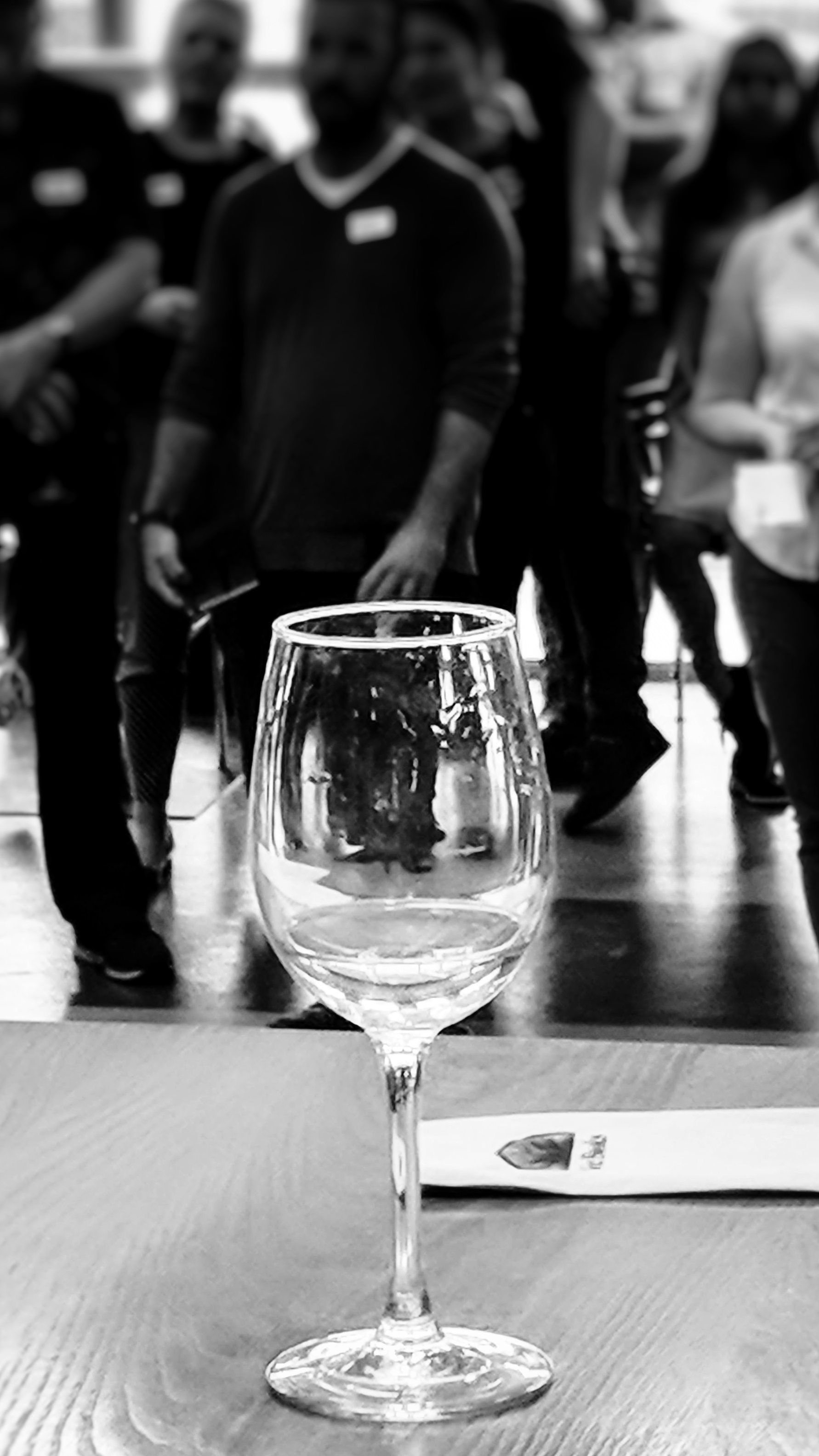 Black and white photo of a wine glass in front of people