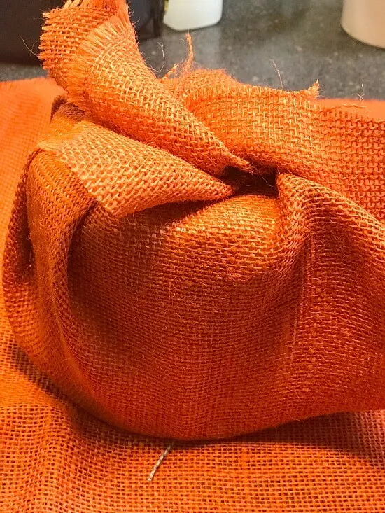 Orange burlap wrapped around toilet paper roll.