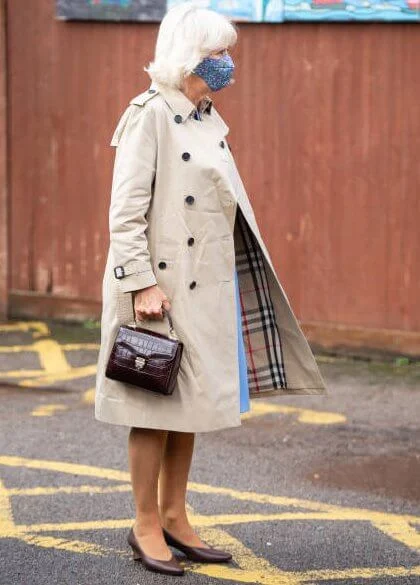 Camilla, Duchess of Cornwall wore a blue wool midi dress, and the mid-length chelsea trench coat from Burberry. British luxury brand Burberry