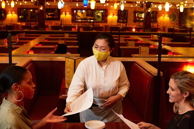 Waiters in mask taking order in reopened restaurant.