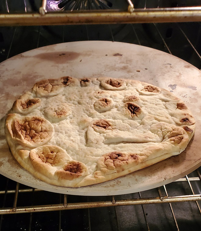 pita bread baking on a pizza stone