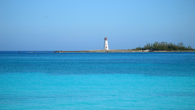 Lighthouse on Paradise Is. surrounded bycalm,  aqua seas.