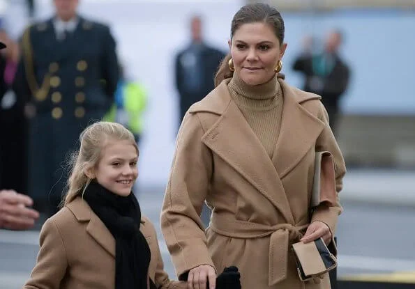 Crown Princess Victoria wore a camel coat by Max Mara, and gold earrings by Sophie by Sophie. Princess Estelle. By Malene Birger clutch