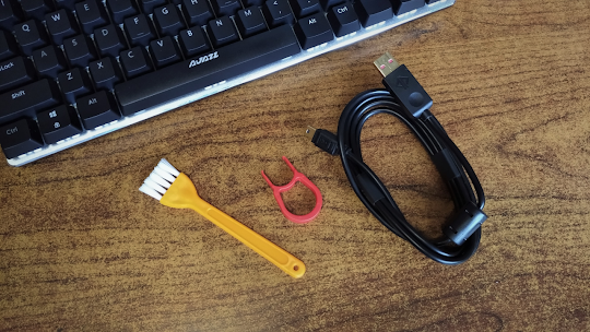 Accesorios del teclado mecánico Ajazz Ak33: brocha para limpieza, extractor de teclas y cable USB desmontable.