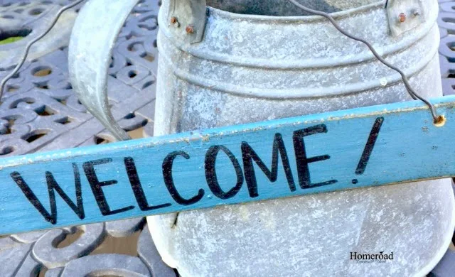welcome sign hanging on galvanized watering can
