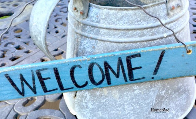 welcome sign hanging on galvanized watering can