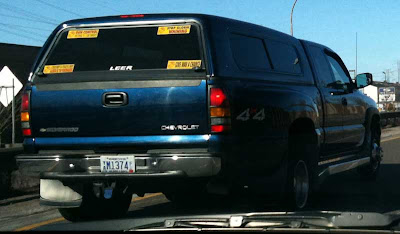 Blue full size pickup truck with four yellow bumper stickers in the back window, two on the right read Stop Global Whining and Give War a Chance