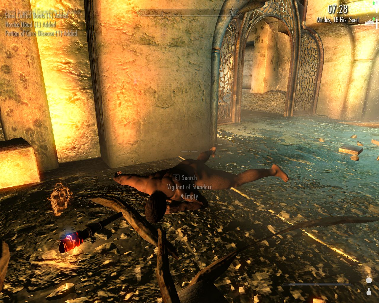 dead man with a light brown skin lies face down in a stone corridor, he has dropped a burning torch on the floor