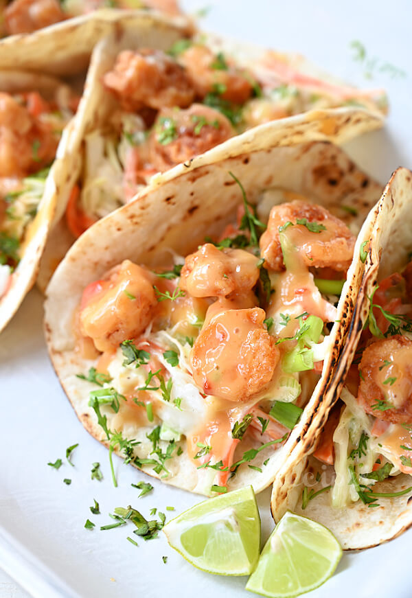 delicious bang bang shrimp tacos with bang bang sauce garnished with cilantro and lemon wedges