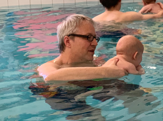 A dad holding a baby while he swims taking his baby swimming for the first time and getting tips as part of swimming lessons