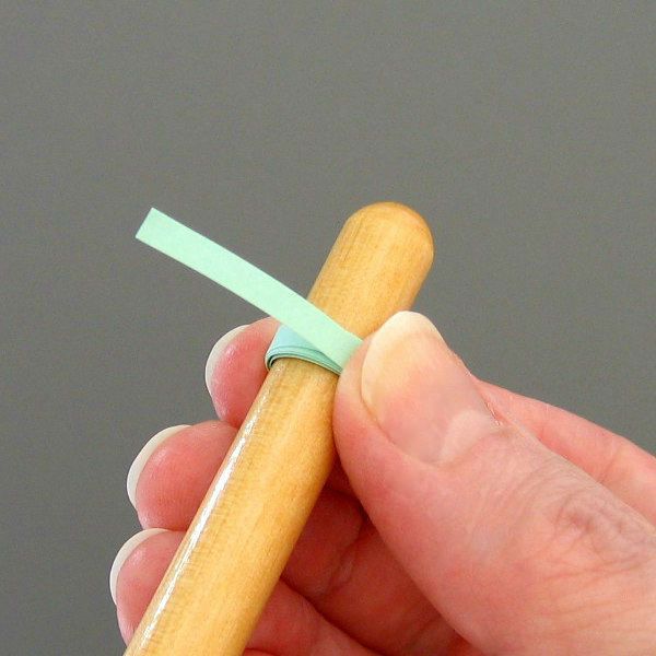 hand showing a rolled paper coil on quilling needle tool