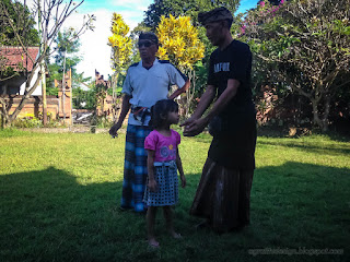 Grandfathers With Balinese Costume Takes Care Of His Granddaughter In The Temple Area
