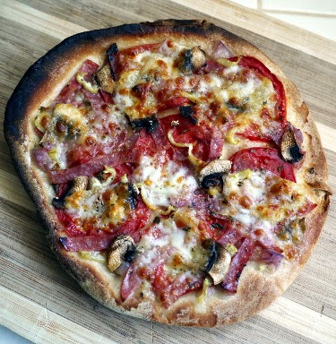 pita pizza cooked in toaster oven with mozzarella, salami, eggplant pickle, heirloom tomato, and hot pepper