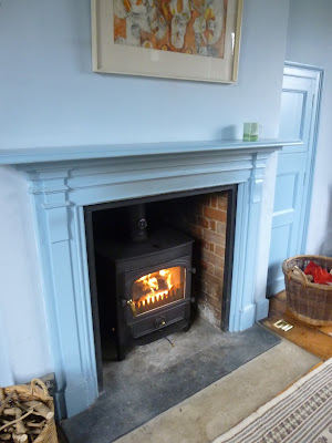 Picture of the newly-installed woodburner with flames, in the blue room fireplace, since moving to the country