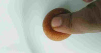 Pressing  gulab jamun ball to check if cooked or not