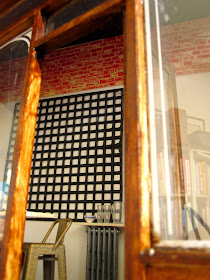 Interior view of a modern dolls' house miniautre cafe, showing a black ceiling made of distressed boards and brick walls below it.