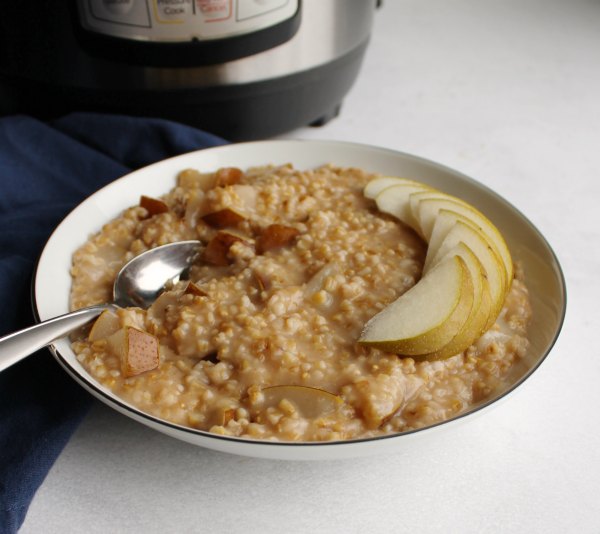 Deliciously hearty steel cut oatmeal flavored with pears, honey and cinnamon is a perfect way to start the day. Make it in a pressure cooker for a quicker and easier hands off breakfast. close bowl of honey pear steel cut oats with fresh pear slices in front of instant pot