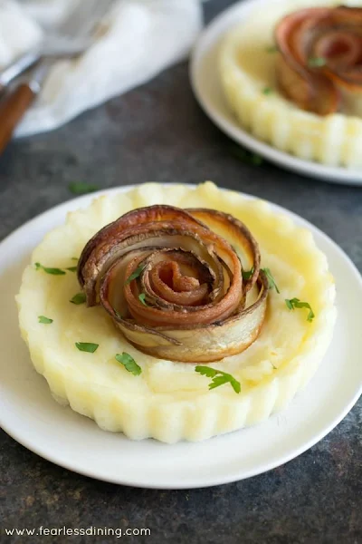 mashed potato pie with potato bacon rosed on a white plate.
