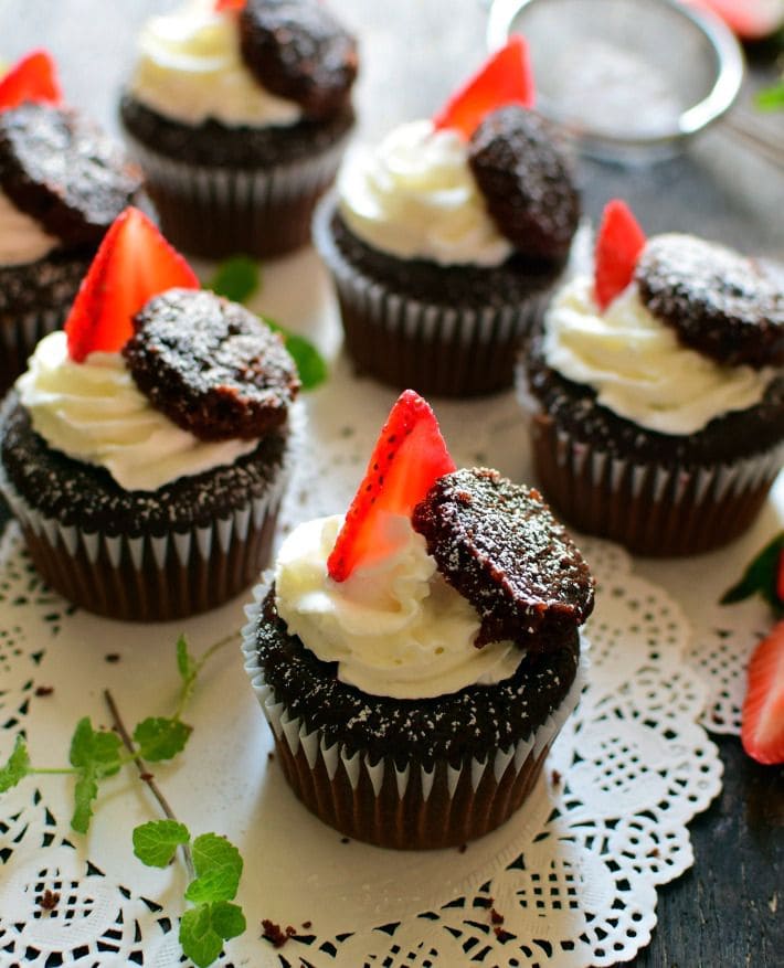 Cupcakes de chocolate rellenos con fresas maceradas, decorados con crema batida, fresas frescas y azúcar glass
